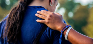 hand with bracelets resting on shoulder of woman